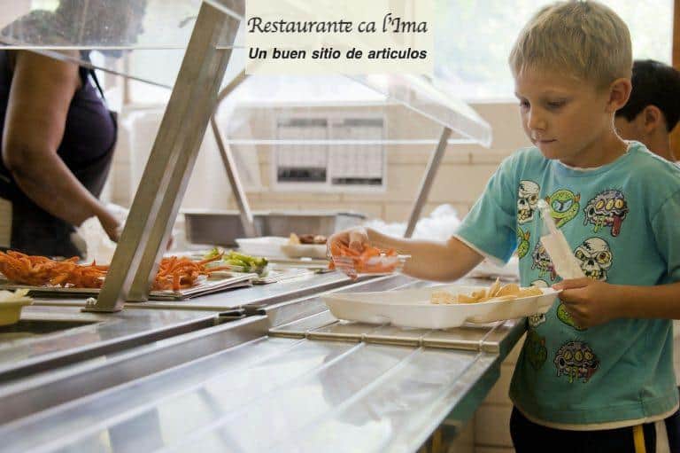 boy in green crew neck t-shirt standing in front of food on table